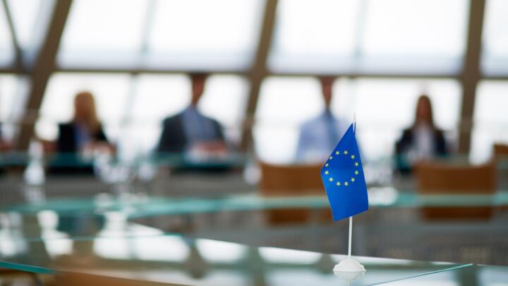 The Social Climate Fund entered into force on 5 June 2023. Image of an EU flag in front of an out of focus boardroom.